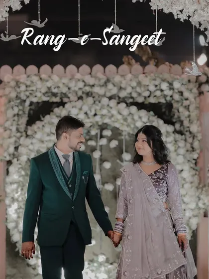 The grand entrance at the Sangeet, set against a stunning floral arch. This image captures the couple walking hand-in-hand, ready to start a night of celebration.