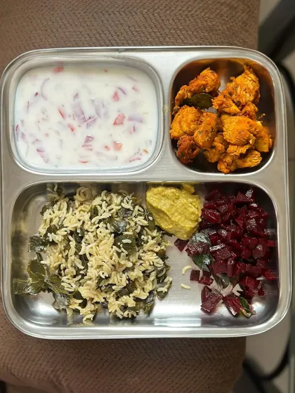 A flavorful meal of spinach rice with chicken 65, beetroot palya, and raita.