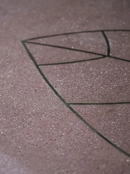 A close-up of the brass leaf inlay, showing the precision with which the metal is set into the terrazzo surface.
