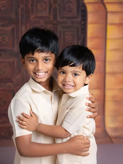 A warm hug between two brothers. Dressed in matching traditional outfits, their smiles and embrace show the strong connection they share.