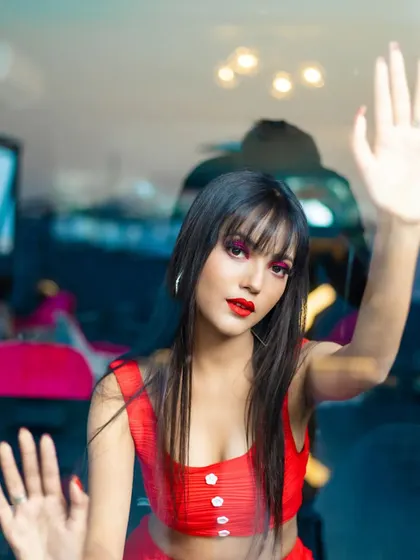A close-up from a modern commercial shoot. The focus here is on the clean, bold makeup with sharp red eyeshadow and a matching lip, paired with sleek hair and bangs for a contemporary and chic vibe.