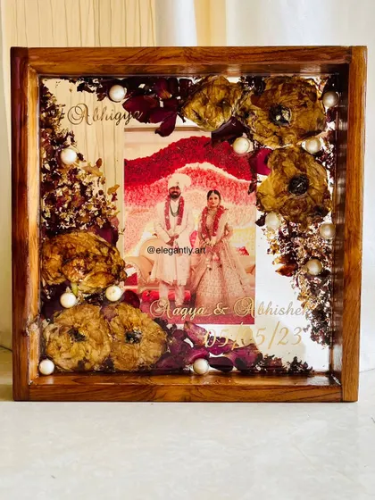 A beautiful 10-inch teakwood frame preserving a wedding garland. The flowers are arranged to create a lovely border around the couple's photo, making it the focal point.