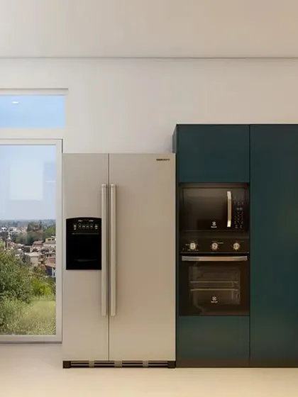 A bold and modern kitchen design with deep teal cabinets and a striking geometric backsplash. The layout is designed for efficiency, with the refrigerator, oven, and sink forming a perfect work triangle.