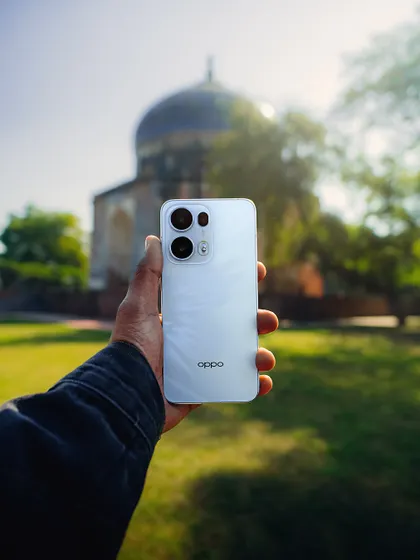 Holding the OPPO Reno13 against the backdrop of a historic Delhi monument. This type of shot connects the product directly to the creative process and the beautiful results it can produce.