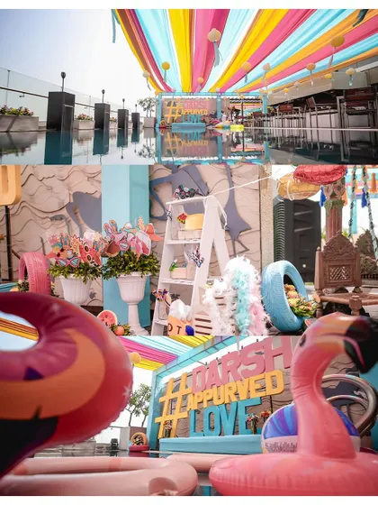 A look at the fun and quirky decor of a poolside pre-wedding party, complete with colourful drapes, flamingos, and custom signs.