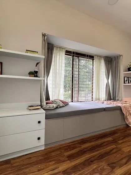 A close-up of the custom window seat in the children's bedroom. Flanked by open shelves and drawers, this cozy nook is designed for relaxation and provides ample storage for books and toys.