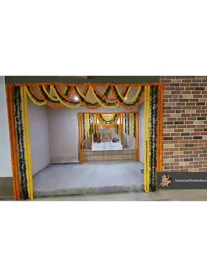 An entrance to a pooja room within a corporate building, decorated with traditional marigold and mango leaf garlands. This creates a clear and auspicious entryway for prayer.