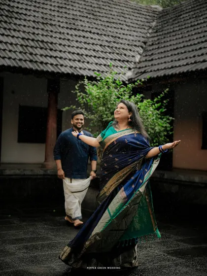 Embracing a spontaneous shower of rain in the courtyard. This candid moment from a Kerala pre-wedding shoot is a beautiful symbol of embracing life's journey together.