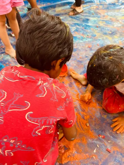 Children dive into the colors during our Holi celebration. Sensory experiences like this are essential for learning, allowing them to explore textures and materials with their whole bodies.
