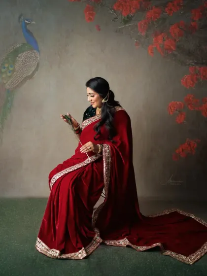 A solo portrait with a touch of nature. The mom-to-be, in her red velvet saree, is framed by a peacock and floral elements, adding to the artistic feel.