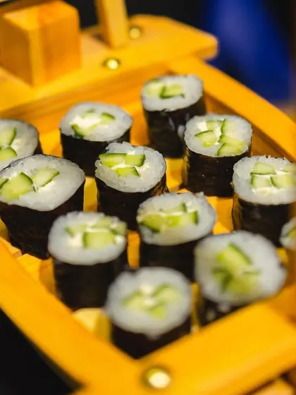 Cucumber maki rolls presented in a bright yellow sushi boat.