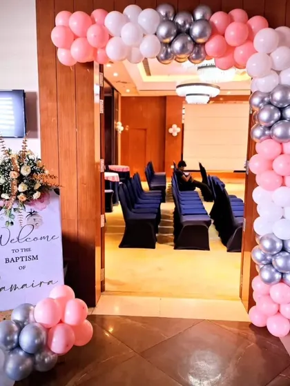The welcome entrance for Samaira's Baptism party. A custom welcome sign and a beautiful balloon arch in pink, white, and silver greet guests as they arrive.