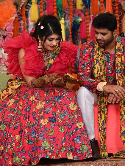 A quiet moment between the couple amidst the celebration. The rich textures and colours of the Mehendi decor, from the floral arrangements to the patterned textiles, create a warm and intimate setting.