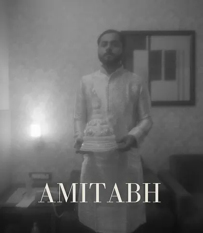 A moody and atmospheric portrait of the groom, "AMITABH," holding his 'topor'. The soft focus and black and white style give it a timeless, cinematic feel.