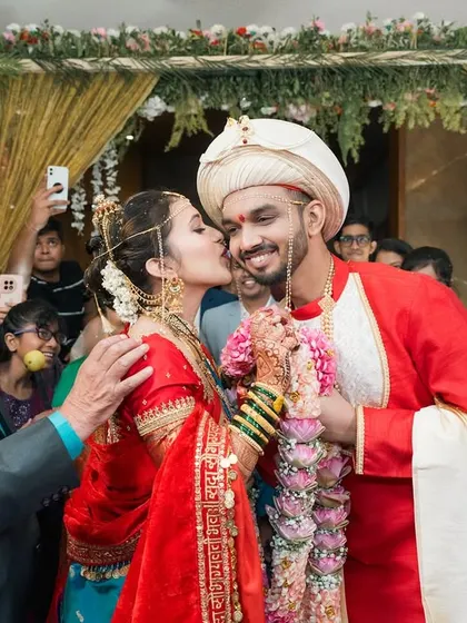 A sweet kiss from the bride amidst the joyful chaos of the wedding rituals. A perfect candid moment surrounded by smiling family.