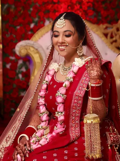 Shreya looks absolutely radiant on her wedding day. Her classic red lehenga is paired with a soft, glowing makeup look and a beautiful rose garland, capturing the joy of the moment.