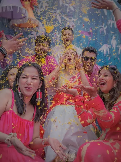 A moment of shared joy as the bride and her friends are showered in flower petals during the Haldi ceremony.