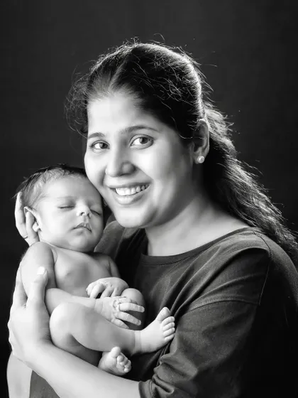 A mother's radiant smile as she holds her sleeping newborn. This classic portrait captures the deep, instinctual love between a mom and her baby.