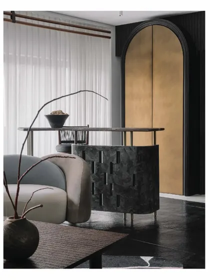 The informal bar in the 'Aria' living room is a crucial centerpiece. We designed it with a unique perforated pattern in dark stone, making it a sculptural element that overlooks the main seating area and connects the room.