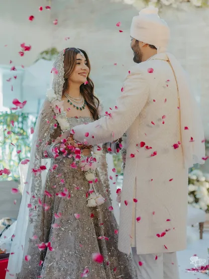 The couple shares a look during their ceremony, surrounded by a sea of white florals and elegant decor, creating a serene and pure ambiance.