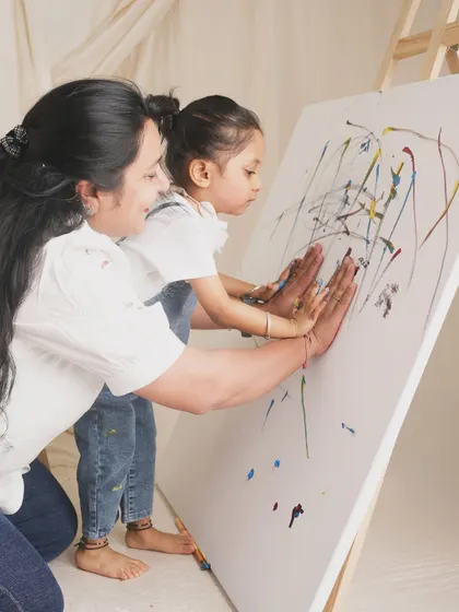 A mother and daughter create a piece of art together, pressing their painted hands onto a canvas. A wonderful way to capture a shared creative moment.
