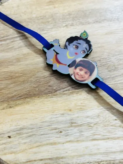 A sweet rakhi for a young boy, featuring an image of little Krishna alongside his own photo.