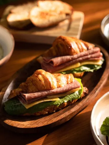 A close-up of a ham and cheese croissant at Kaia Goa. The warm, flaky pastry and fresh ingredients are the focus of this delicious-looking sandwich shot.