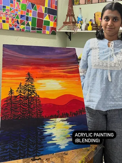 A student stands proudly with her completed landscape painting. She learned to use acrylic blending techniques to create the smooth gradient of the sunset and the reflection in the water.