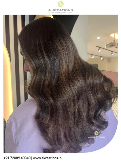 A client enjoying her new look, featuring soft brown highlights and gentle waves that add confidence and style.