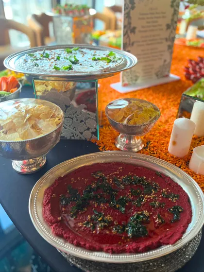 A close-up of our vibrant dip selection, featuring a rich beetroot hummus and a creamy white bean dip. Served in elegant silverware with fresh garnishes, these dips are a beautiful and delicious part of our grazing tables.