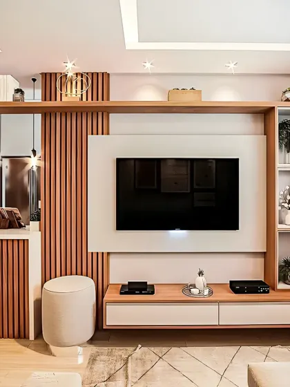 This living room design features a full-wall entertainment unit with vertical wood slats and a mix of open and closed storage. A small, integrated vanity or bar corner adds extra functionality to the space.