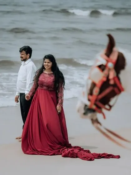 Another perspective of the couple on the beach with a horse, this time with the bride's flowing red dress as a central element.