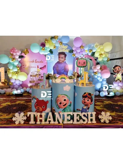A colorful Cocomelon themed first birthday for Thaneesh. The stage features all the favorite characters on pedestals, a personalized backdrop, and a pastel balloon arch.