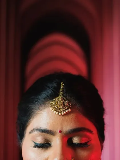 An artistic close-up of the bride's maang tikka, using dramatic lighting and architectural lines.