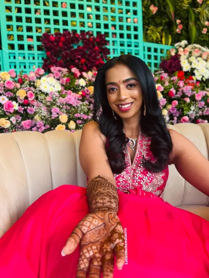 A happy bride showcasing her beautiful mehendi. The design combines the purity of lotuses with the elegance of peacocks for a masterpiece finish.