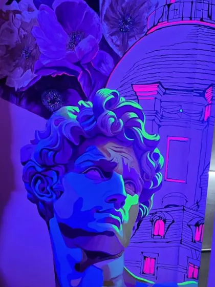 The 'Raahi' mural has a secret. Under UV light, hidden neon colors are revealed, transforming the artwork and creating a completely different vibe for the evening. This shot shows the classical bust glowing with electric colors.