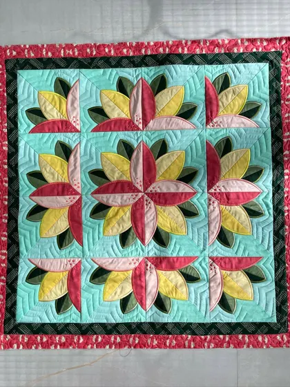 A "Big Bloom" wall quilt featuring nine large, stylized flowers. The ruler work quilting in the background creates a geometric contrast to the curved petals.