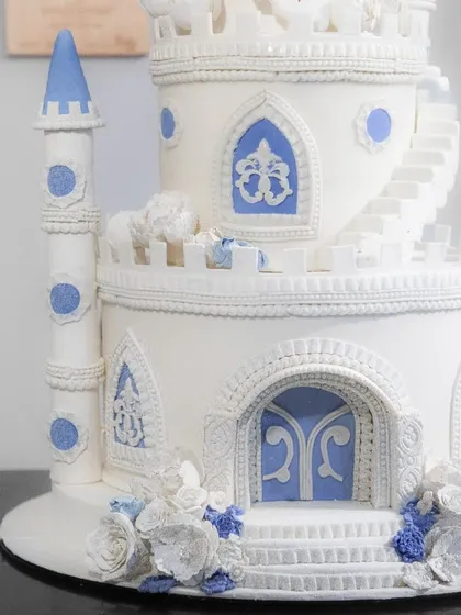 The lower tiers of the castle cake, showing the detailed entrance and delicate sugar flowers.