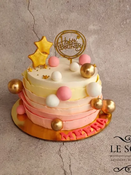 I love finding ways to reduce fondant, so for this cake, I used buttercream ruffles instead. This half-kg Chocolate Butterscotch cake has a beautiful pink ombre effect and is decorated with edible spheres.