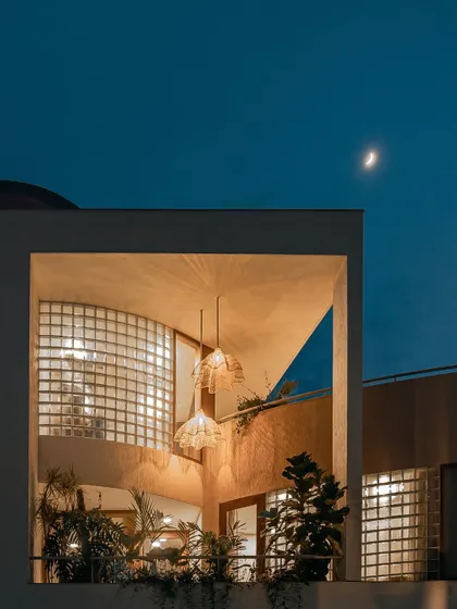 This series of images shows how the home's exterior transforms from day to night. The glass block walls, which provide privacy during the day, become luminous features in the evening, creating a warm and inviting aura.