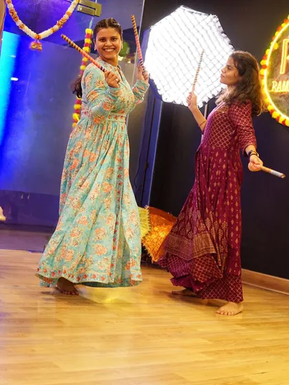 Two friends enjoying a Dandiya dance moment at our studio. We create a friendly atmosphere where you can laugh and learn with your wedding guests.