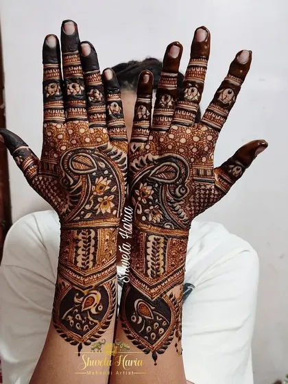 A stunning back-hand mehendi design with intricate details. The pattern features beautiful paisley and peacock motifs, with a bold meenakari effect that makes the design pop.