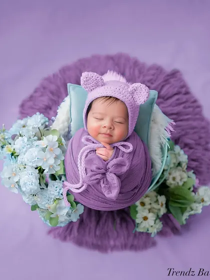 This overhead shot shows a newborn wrapped in purple with a cute bear hat. I love using different angles to capture unique perspectives during a session.