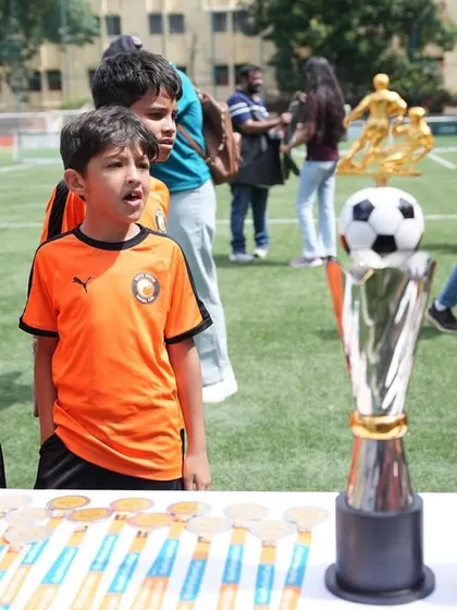 Young players admiring the trophies at the Goal for the Good Cup charity event.