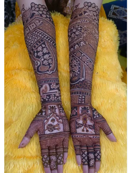 A full-coverage bridal mehndi with a prominent paisley peacock design. The rest of the arm is filled with delicate floral vines and checkerboard patterns, creating a rich and dense look.