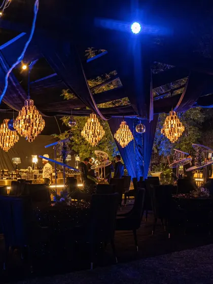 A wider view of the outdoor Diwali party, showing multiple chandeliers and draped fabric creating an opulent and festive canopy for guests.