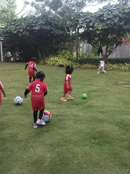 A group of our youngest players, some as young as two, enjoying a football session on a lush green lawn. We believe in starting early to build a lifelong love for physical activity.