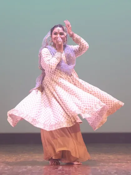 A joyful moment captured during a Kathak performance. The dancer's expression and spinning motion embody the vibrant energy of this classical dance form.