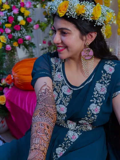 A candid shot of the bride, smiling and showing off her beautiful arm henna. The joy on her face is priceless.