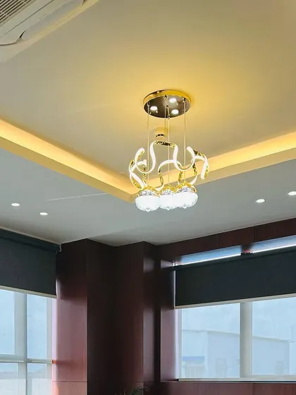 A close-up of the decorative chandelier in the waiting area. Its intricate, swirling design adds a sculptural element to the ceiling and provides warm ambient light.